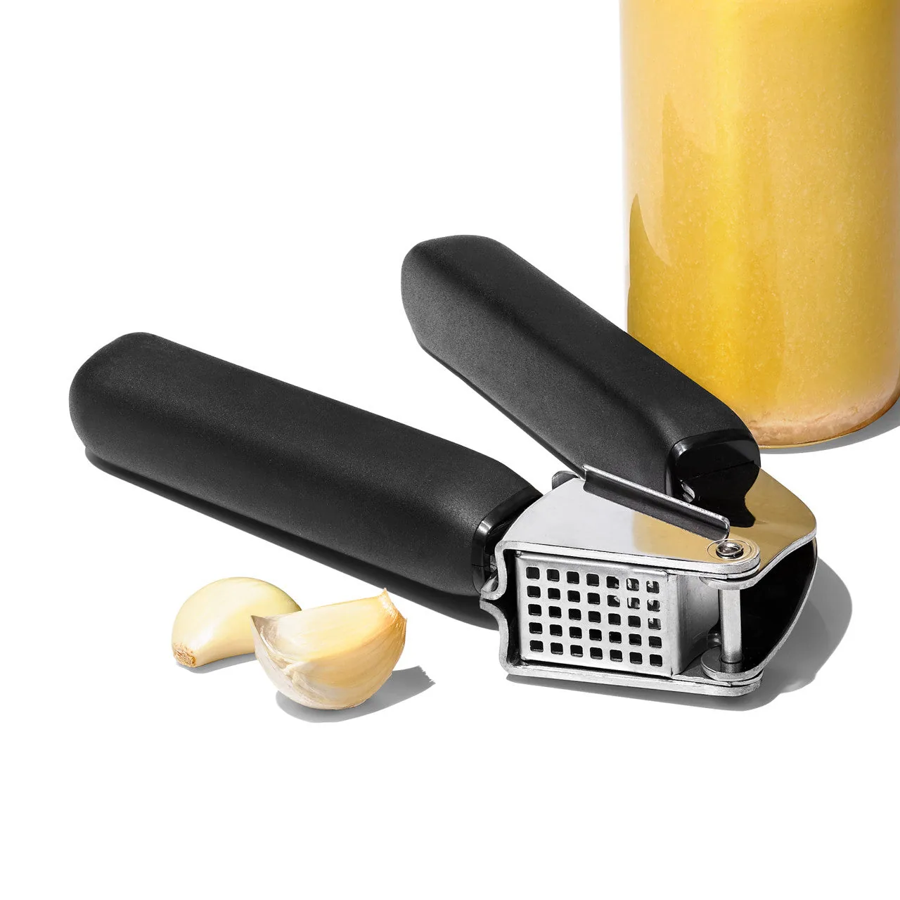 Press shown beside a jar and peeled garlic.