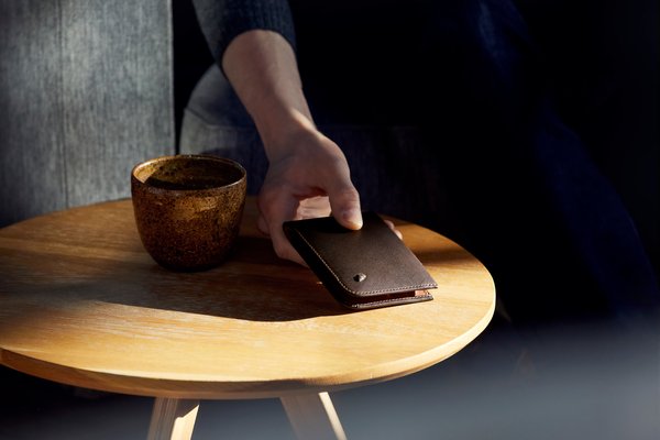 Bellroy Hide & Seek: Manufacturer lifestyle image: the wallet beside a drink gives context, not a precise scale.