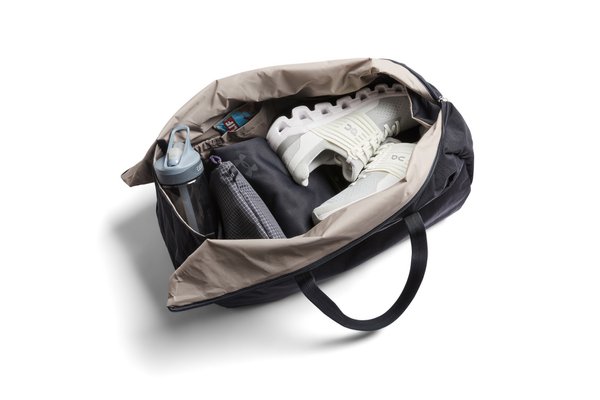 Black Bellroy Lite Duffel open with a light interior and manufacturer-arranged gym belongings