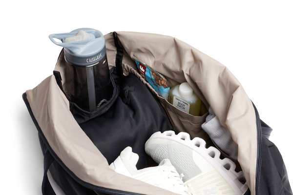 Close view into the Lite Duffel showing a bottle in an end pocket, side organization and shoes in the main compartment