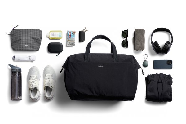 Bellroy Lite Duffel laid out with shoes, a bottle, headphones, clothing and small accessories