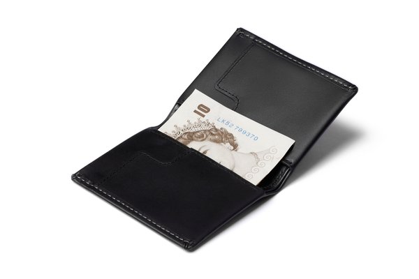 Black Bellroy Slim Sleeve opened with a folded British banknote in the manufacturer's photograph