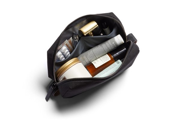 Standard black Bellroy Toiletry Kit opened with manufacturer-arranged bottles, tubes and a comb