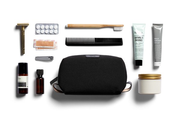 Standard Bellroy Toiletry Kit laid beside a manual toothbrush, grooming tools, tubes and bottles