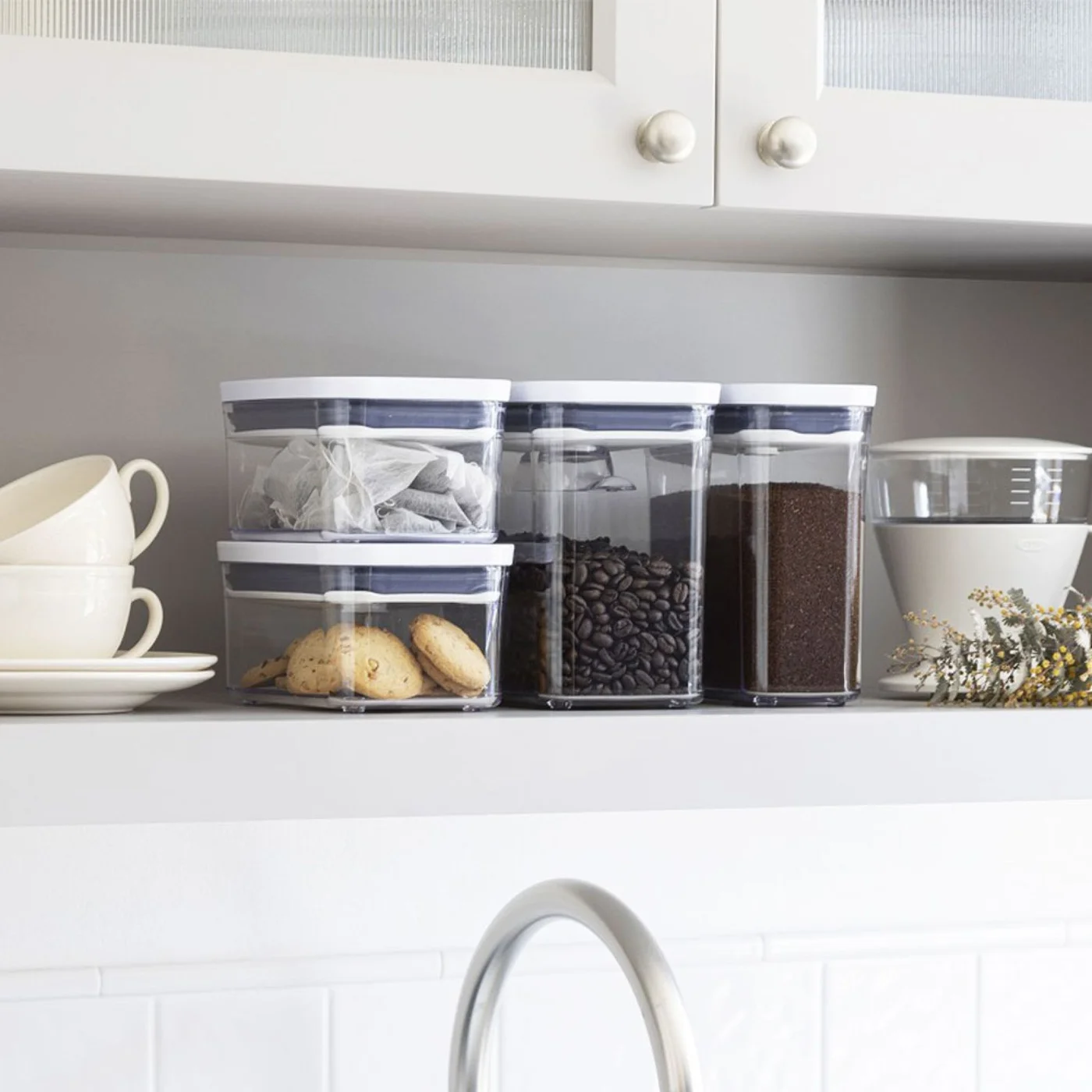 Several differently sized white-lid POP containers on a kitchen shelf