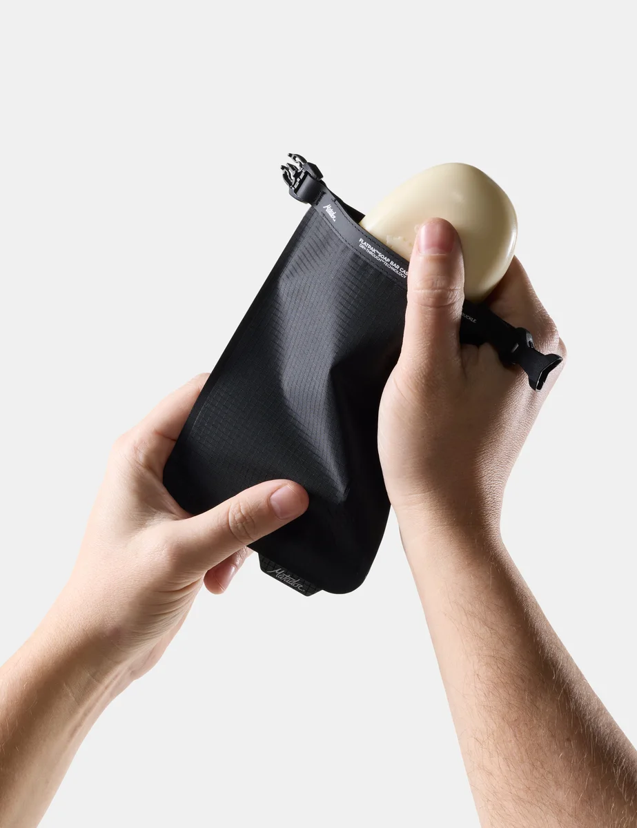 Manufacturer photograph showing a bar of soap being placed in the black Matador FlatPak V2
