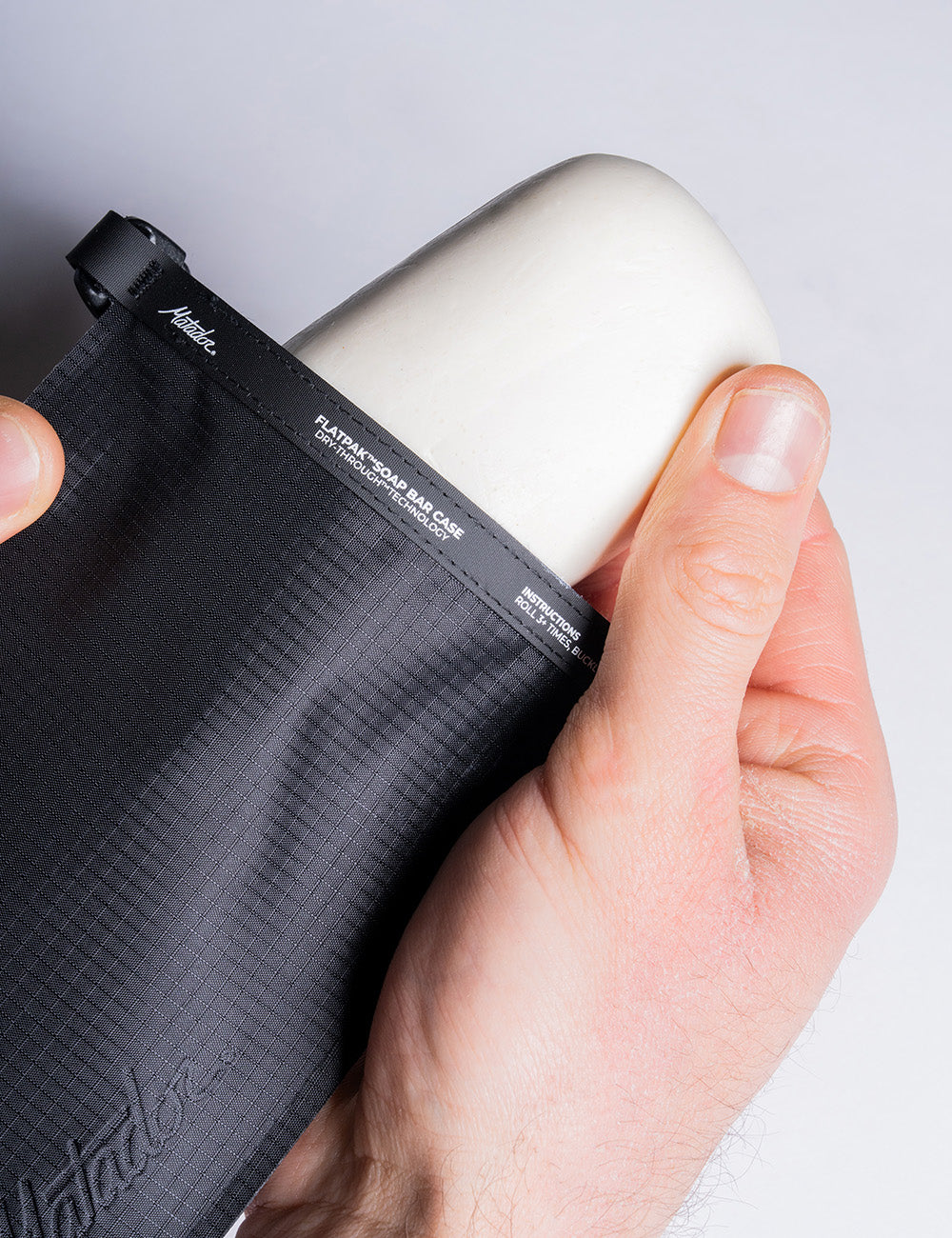 A white soap bar being removed from the black Matador FlatPak V2