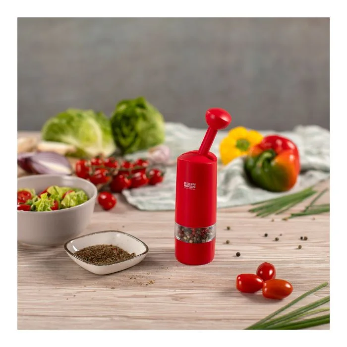 Red grinder placed beside ingredients for meal preparation; food is not included.