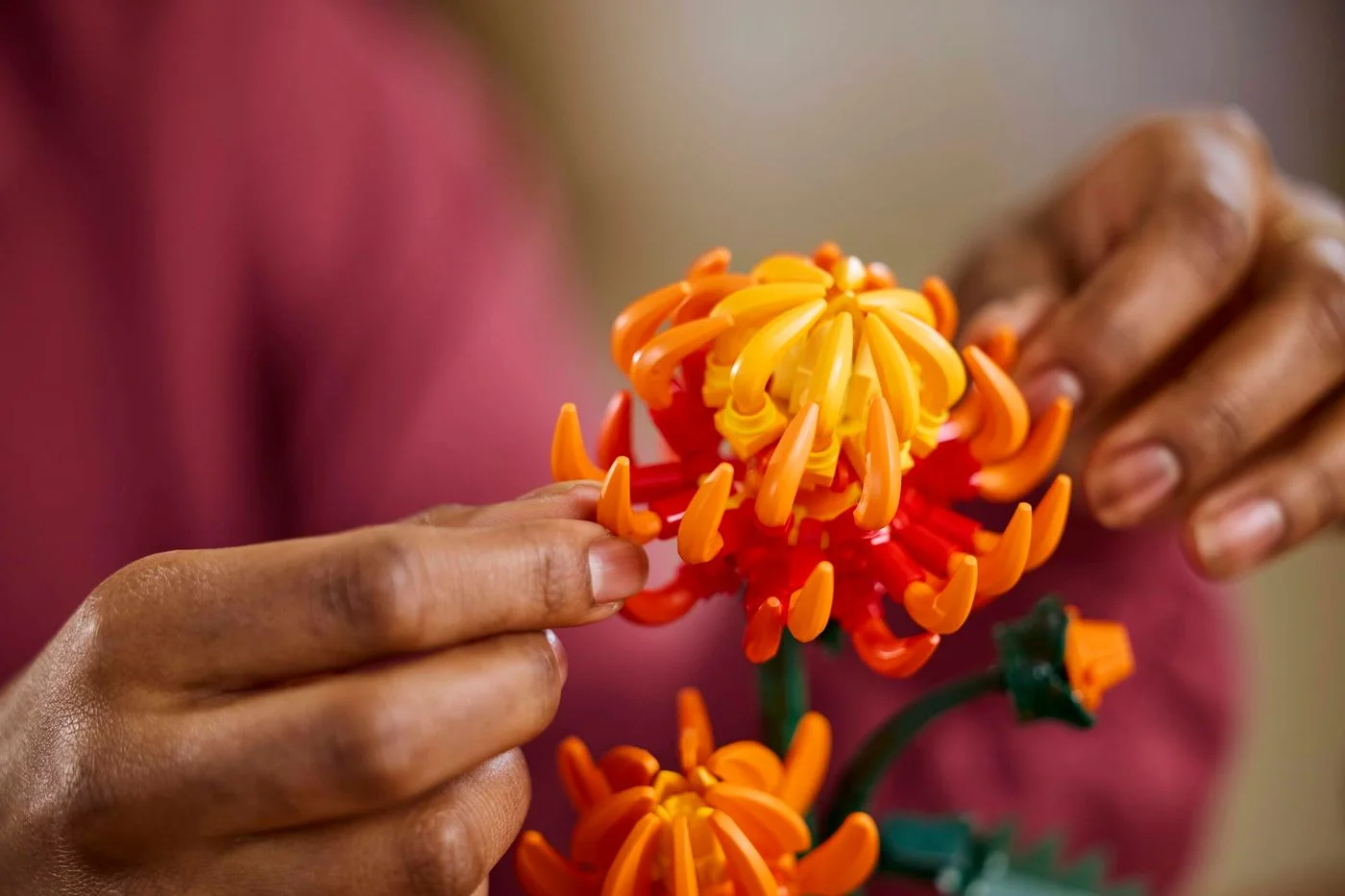 Hands placing flower details during construction; no finished assembly is included.