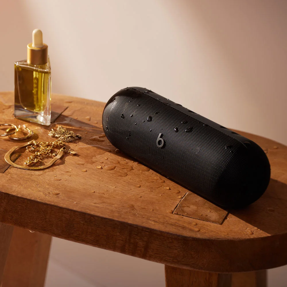 Matte Black speaker on a side table; surrounding accessories are not included.