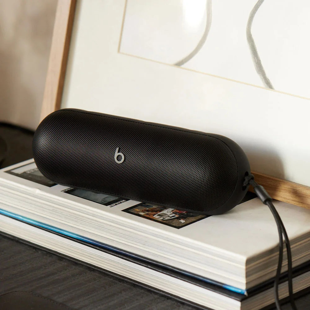 Speaker beside books gives a reference for its tabletop scale.