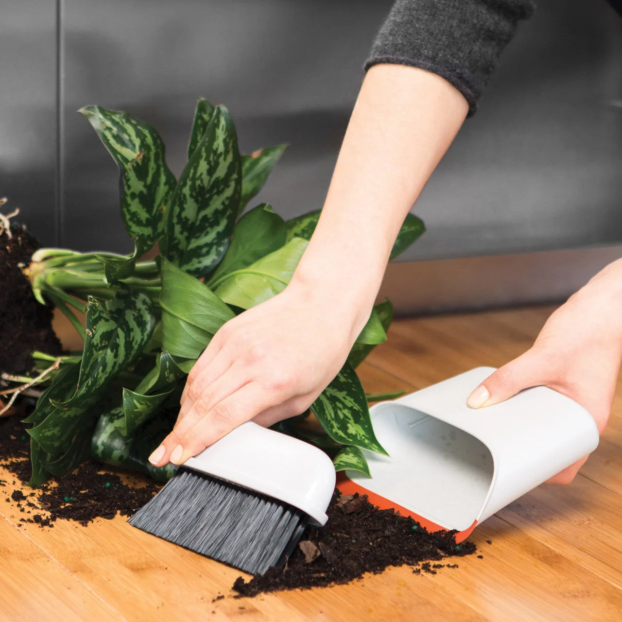 Manufacturer reference scene collecting soil from a tabletop; keep this separate from food-preparation tools.