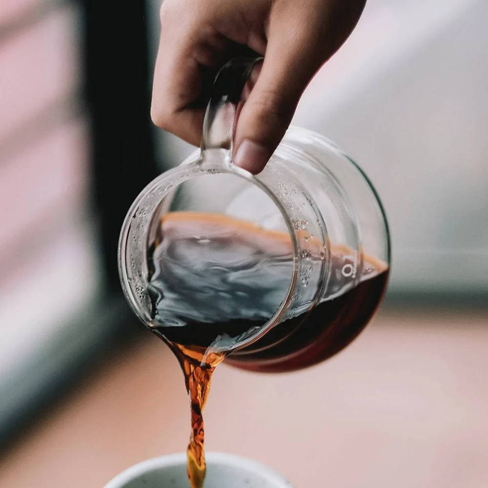 The server pours a prepared brew into a separate drinking glass.