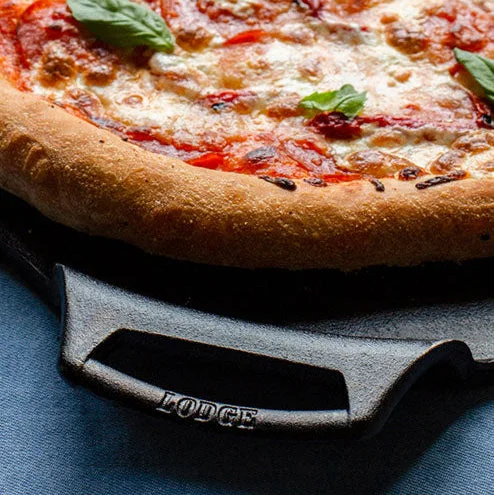Close-up of the raised Lodge handle beside a finished pizza.