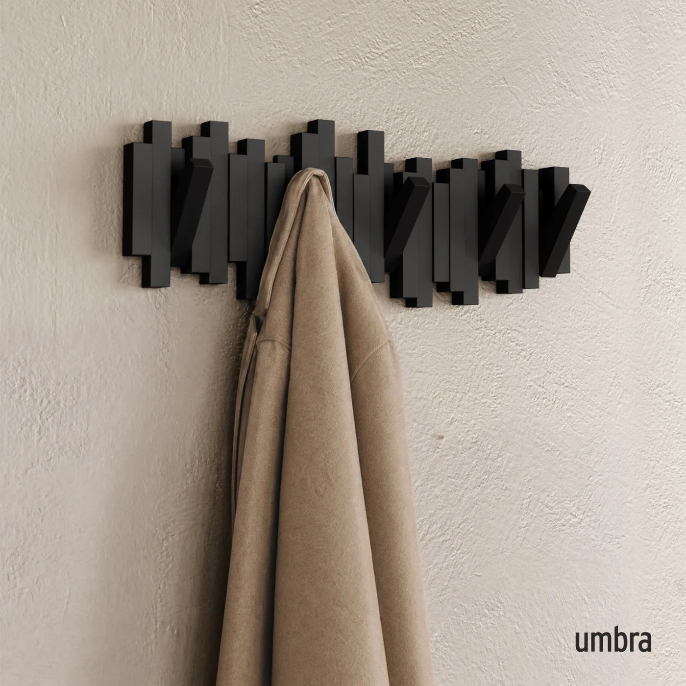 Manufacturer wall scene showing the sculptural rail behind a hanging coat.