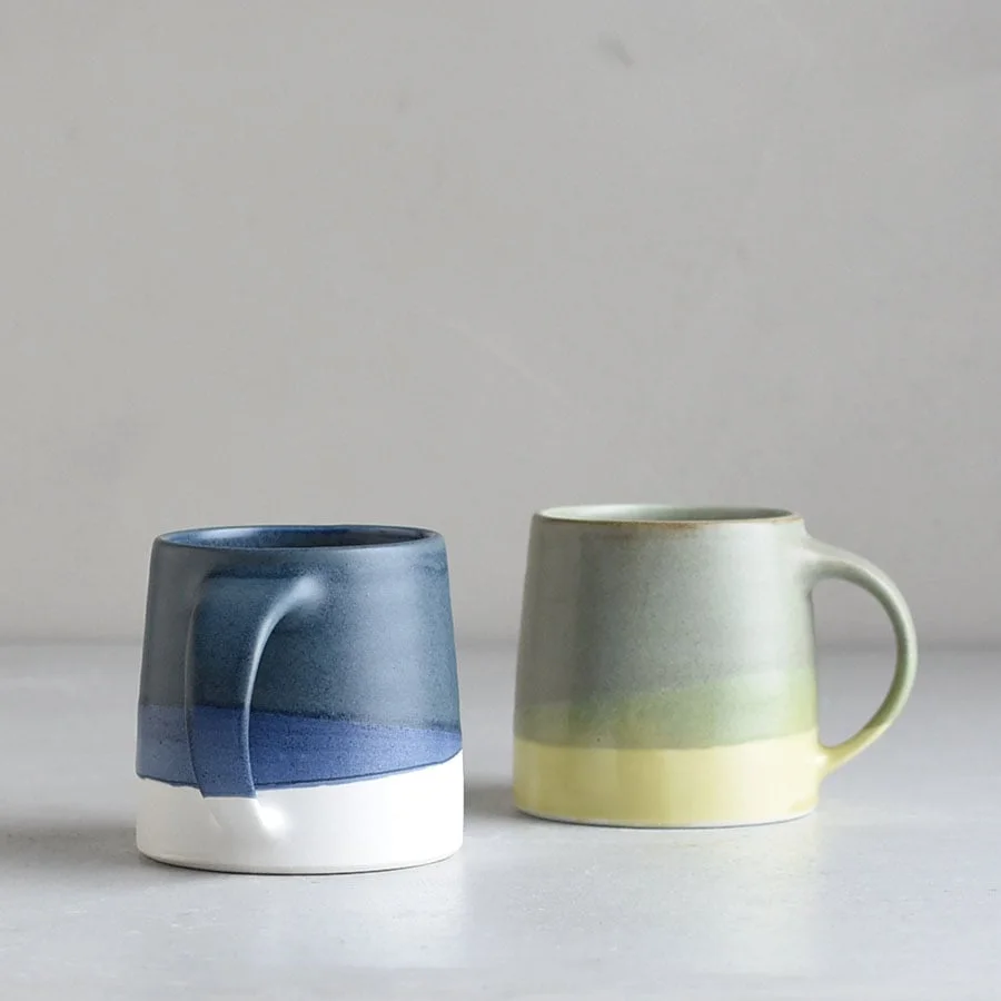 Navy-and-white mug beside the green-and-yellow version; the companion colour is not included.