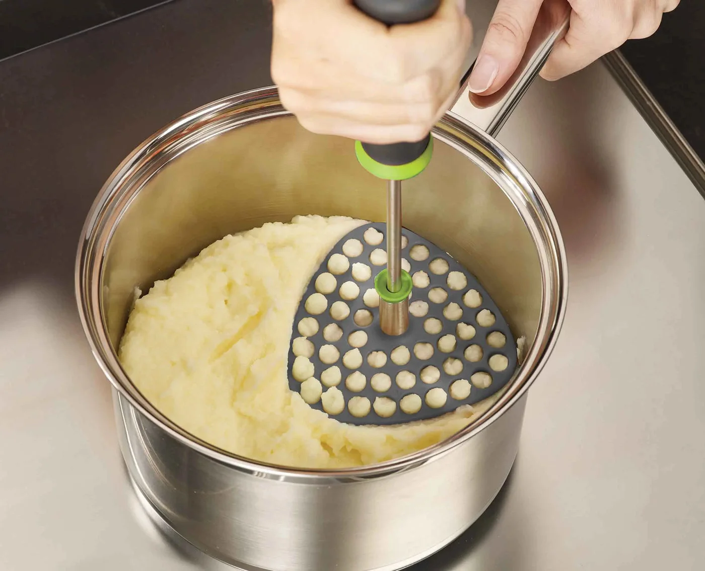 Manufacturer demonstration of mashing cooked potatoes directly in a pan.
