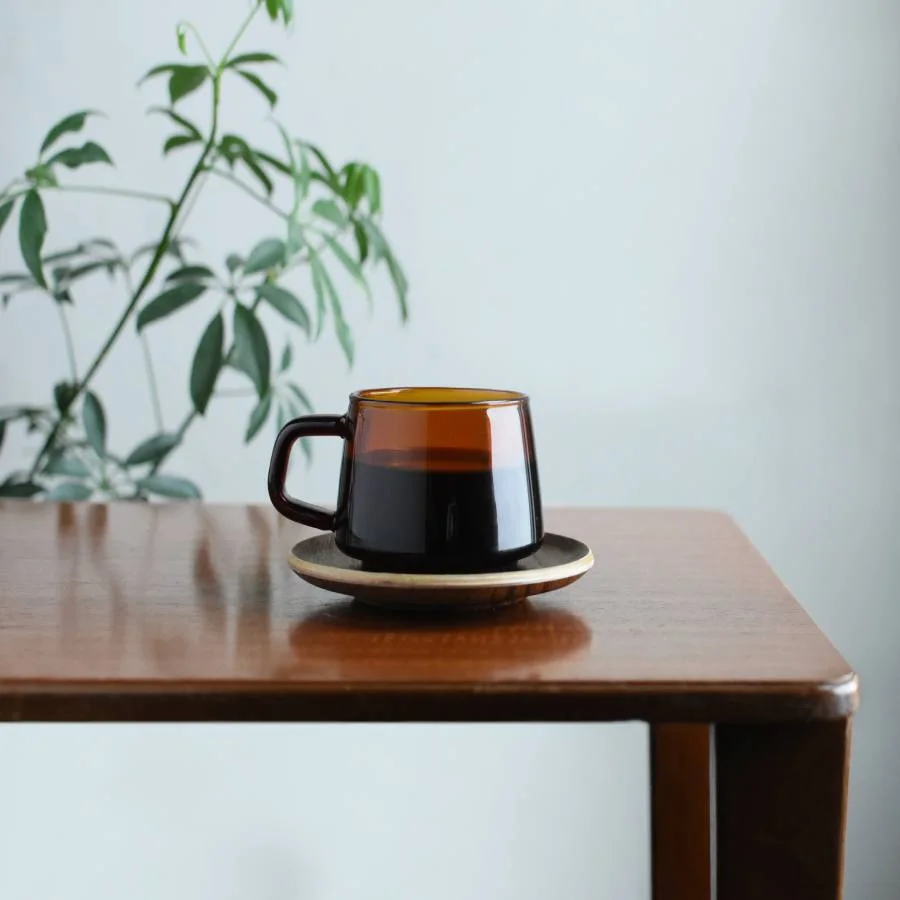 An amber mug in a quiet tabletop scene; saucer and accessories are styling items, not included.