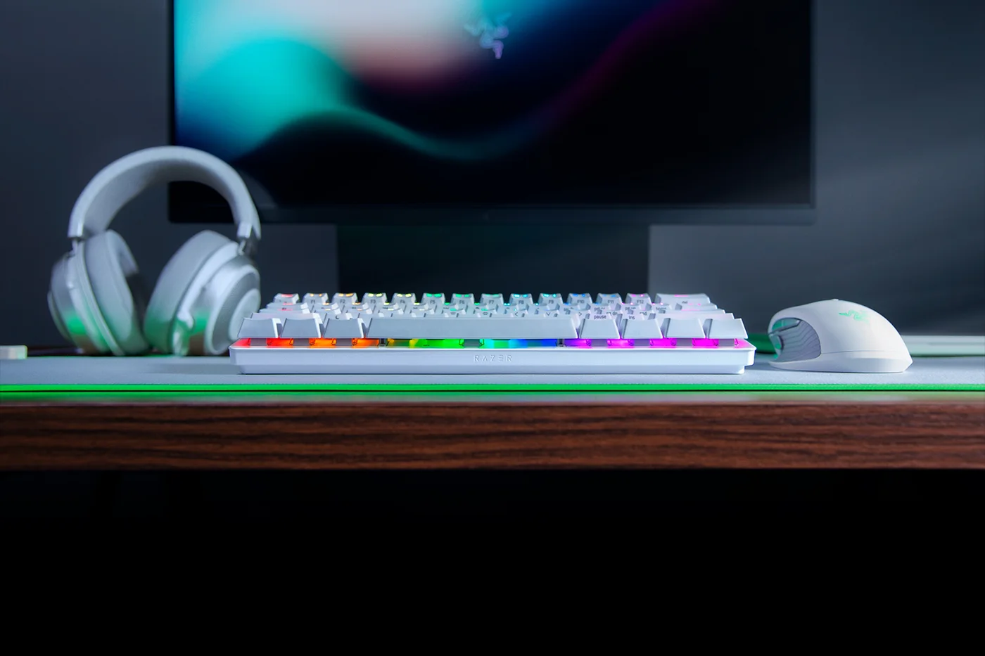 Low-front workstation view shows the compact keyboard; headphones and mouse are not included.