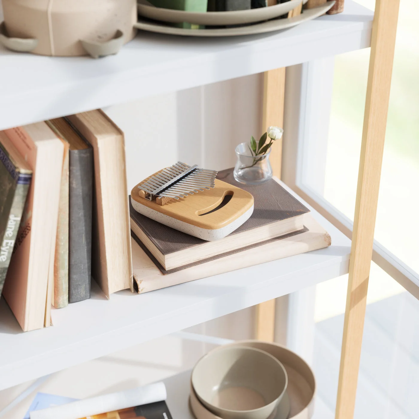 A shelf scene shows the thumb piano among books; the surrounding props are not included.