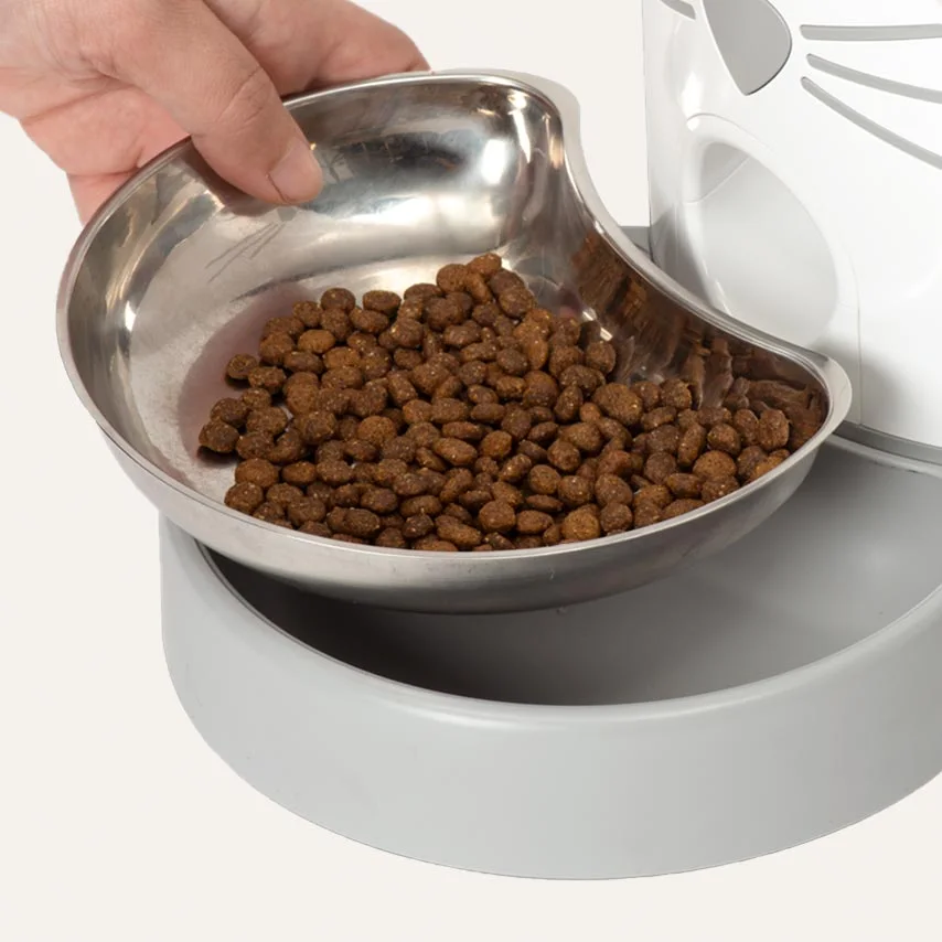 Removable stainless feeding dish being lifted for cleaning.