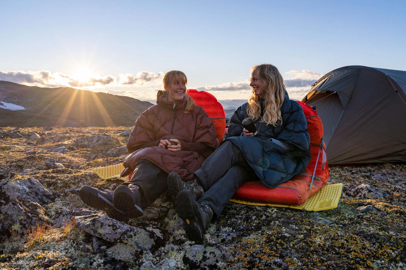 The Burgundy Down model is pictured beside a tent at sunset; other camp equipment is separate.