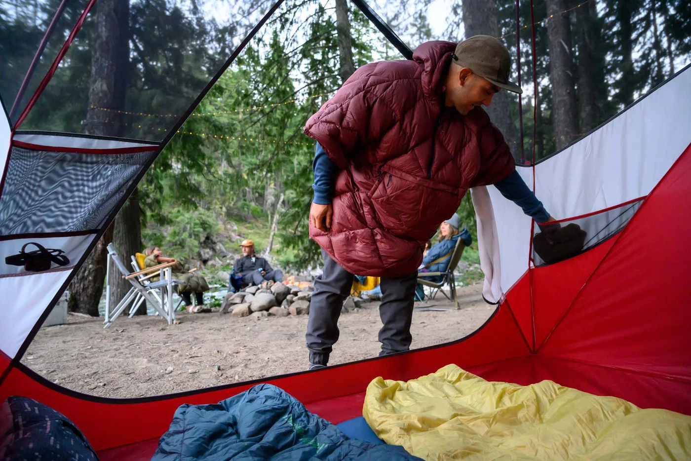 The worn Burgundy poncho keeps the hands available during a campsite routine.