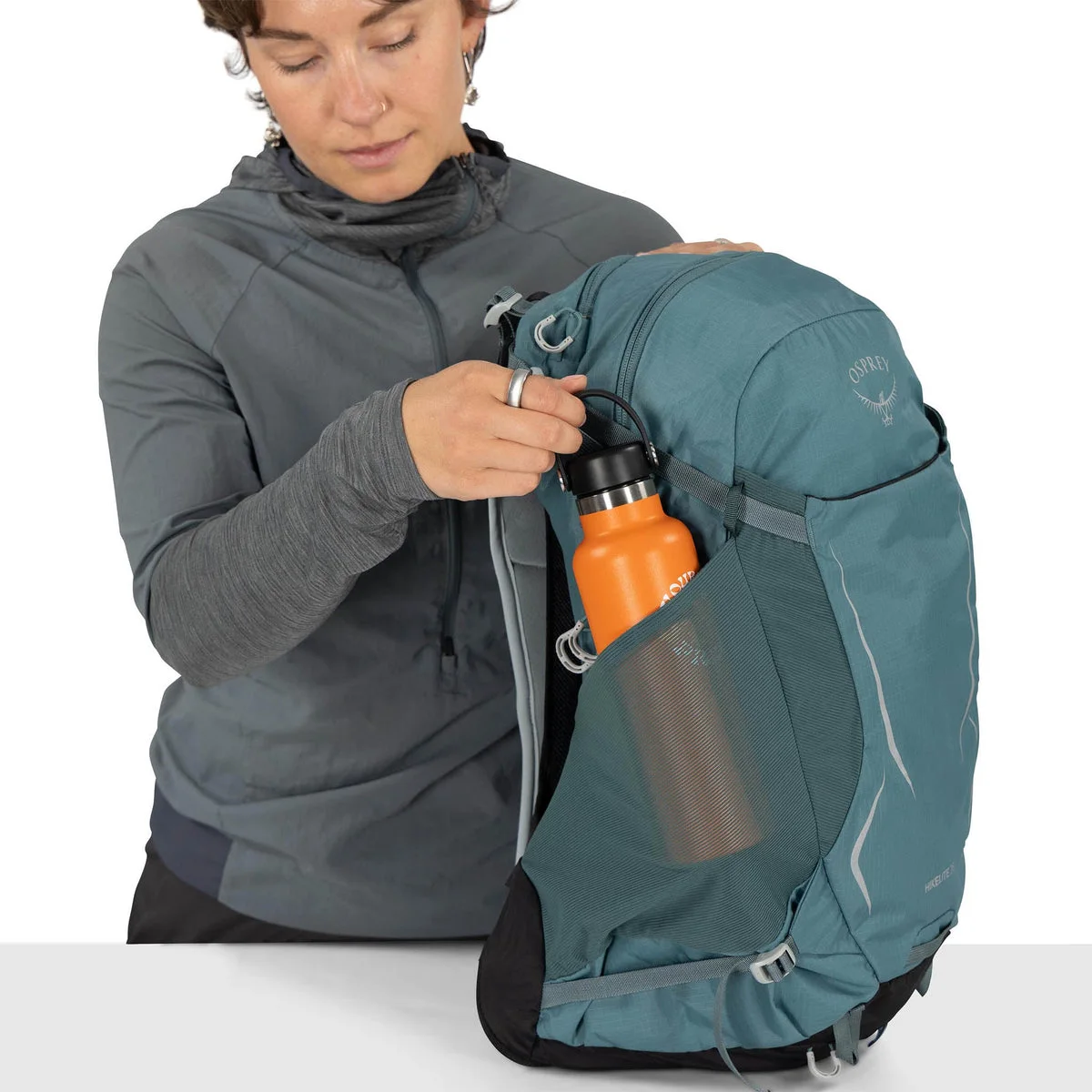 Blue same-model side-pocket demonstration with a bottle prop.