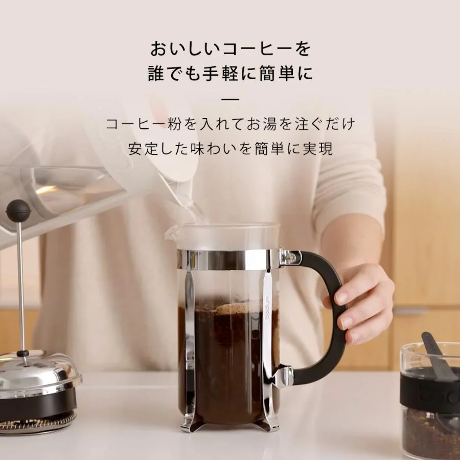 Official brewing scene showing the black handle and polished steel frame.