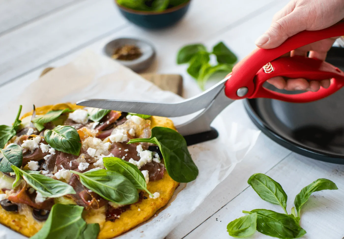 Selected red Scizza cutting a pizza in a maker demonstration; pizza and cookware are separate.