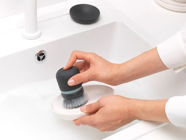 Palm grip shown cleaning an accessible dish surface; not our hands-on test.