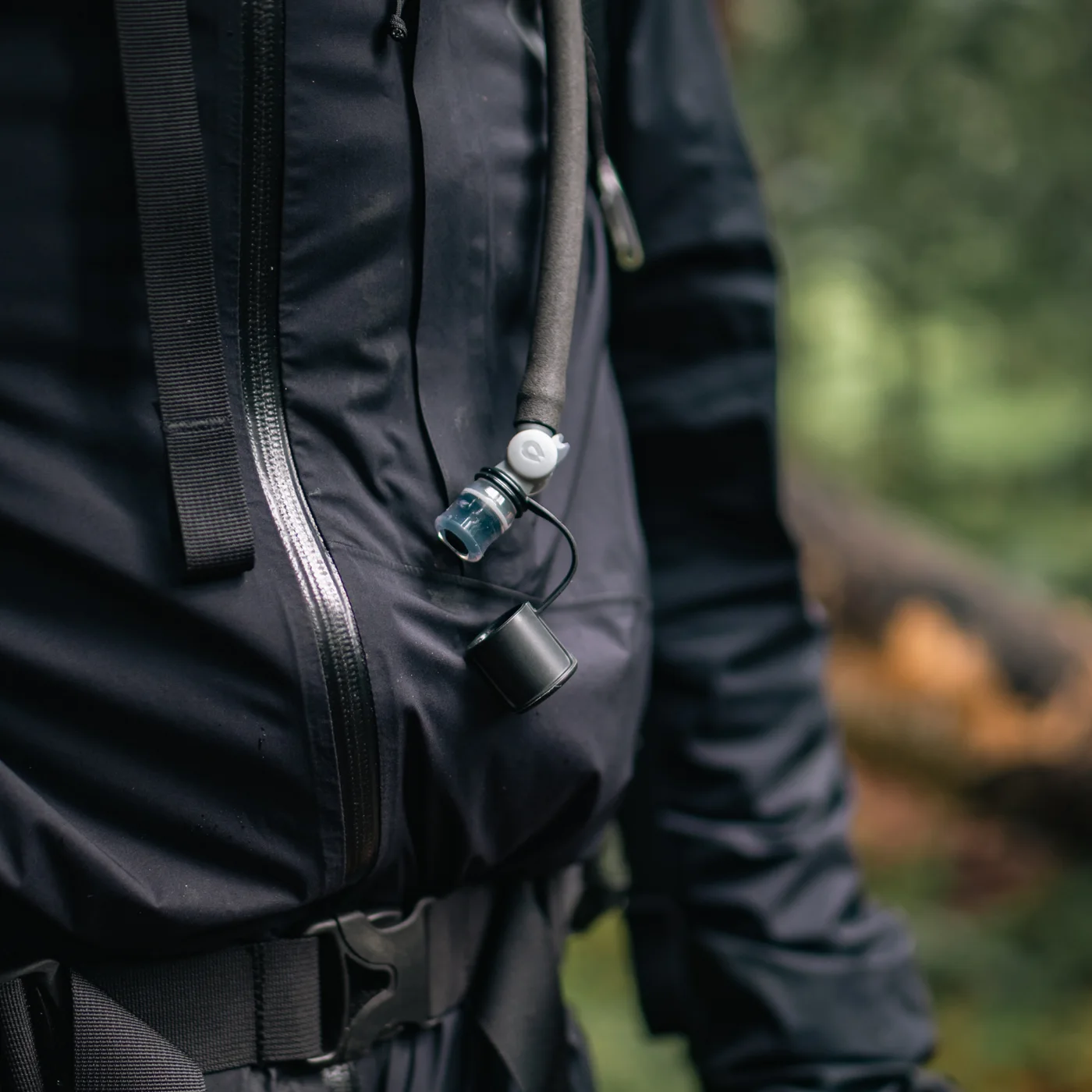 Tube and drinking end routed to a backpack shoulder strap.