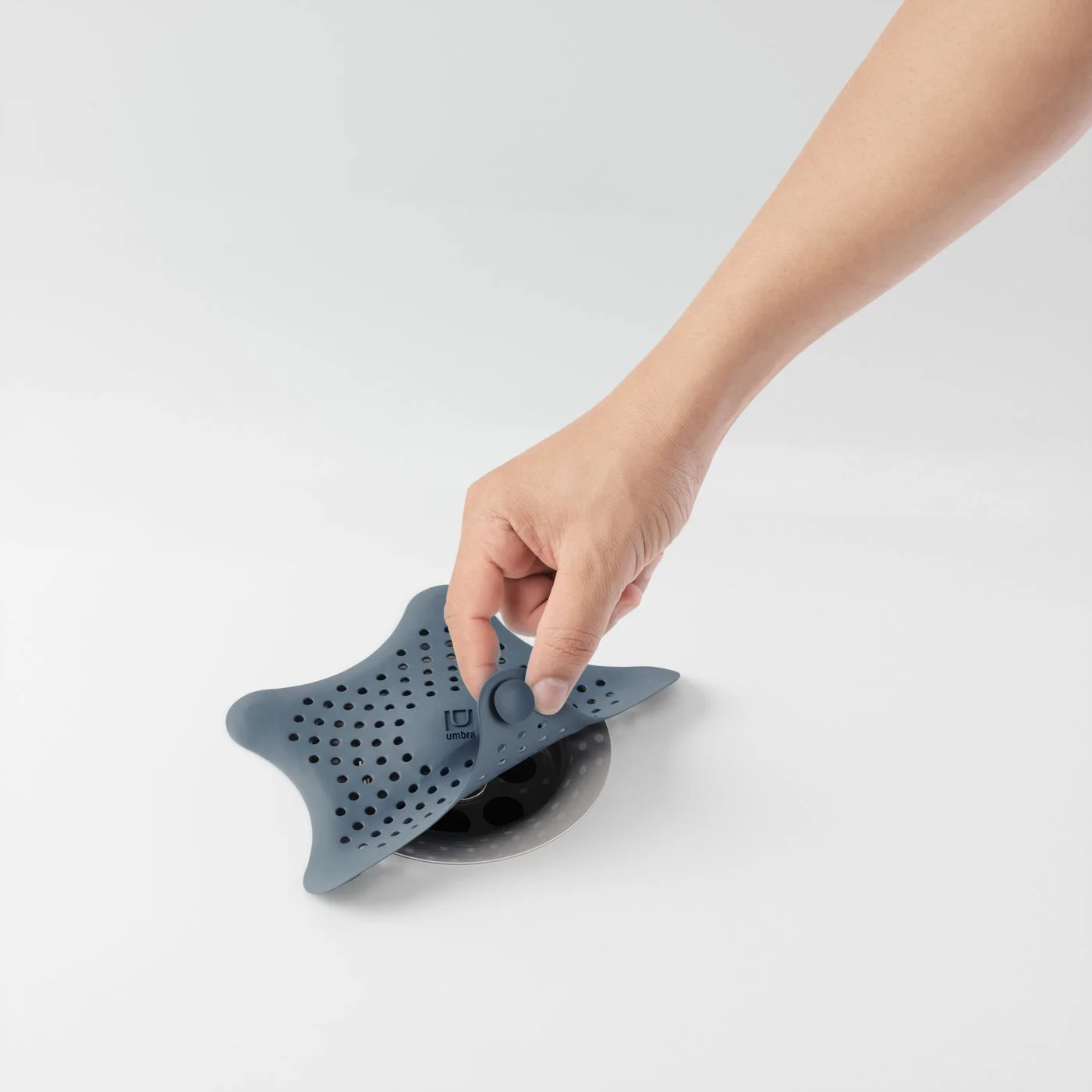 Hand lifting the Slate Blue flexible cover, showing access for removing trapped hair.