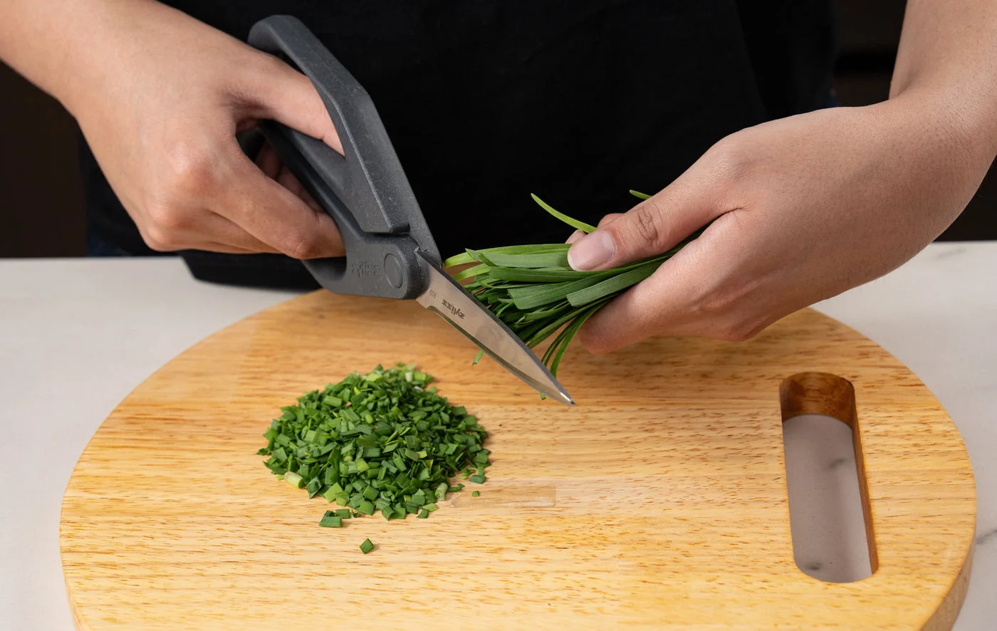 Separate clean pair demonstrated cutting herbs on a board.