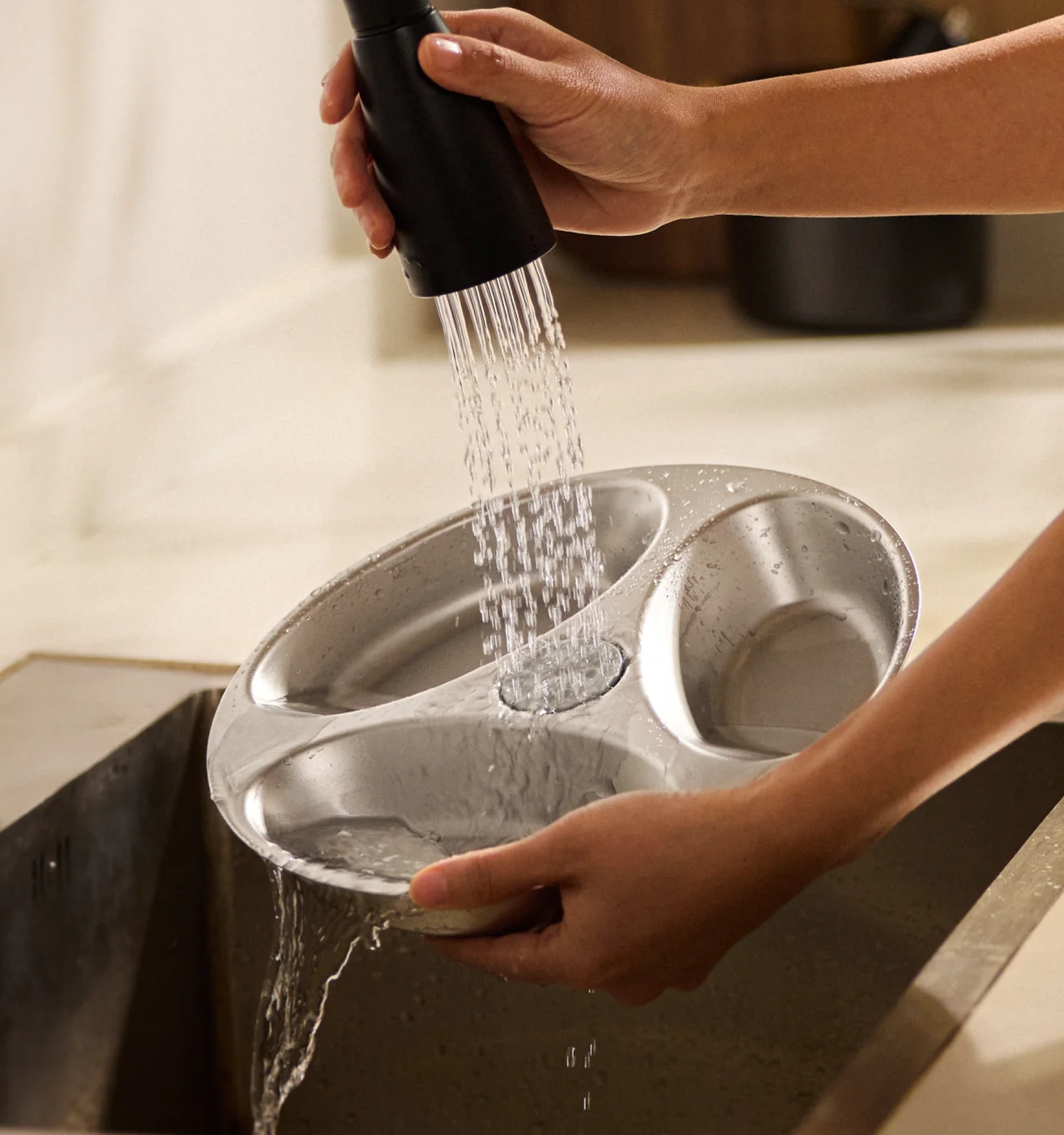 Removable stainless steel tray being washed.